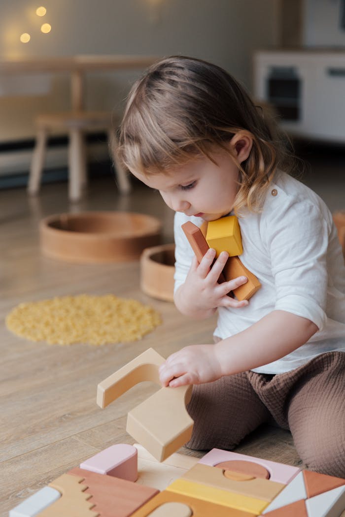 Young child playing with wooden blocks indoors, showcasing innocence and creativity.