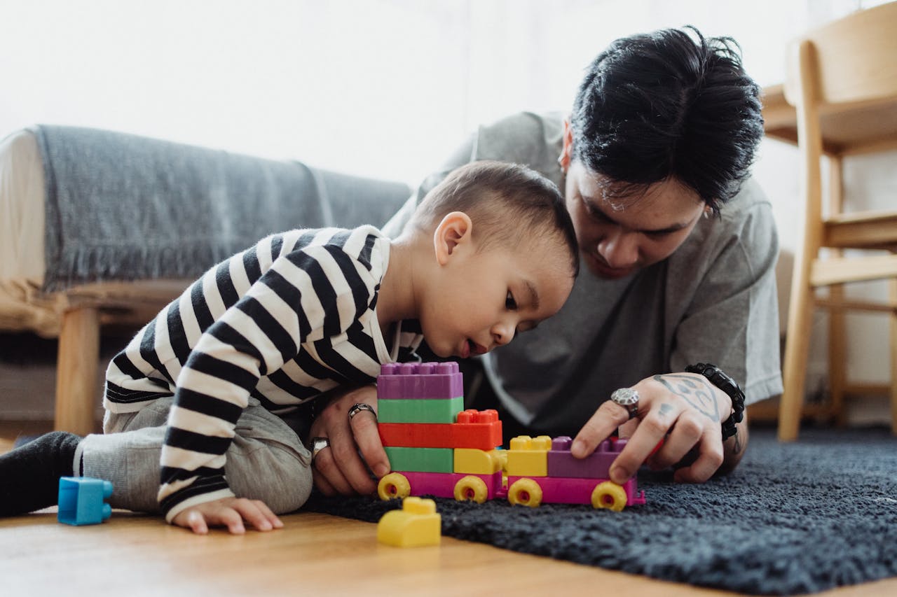 A father and son bonding while playing with colorful blocks indoors.